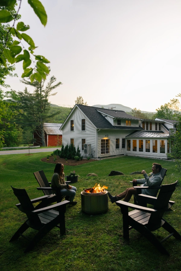 Guests sitting around a fire pit on the lawn with the farmhouse in the background